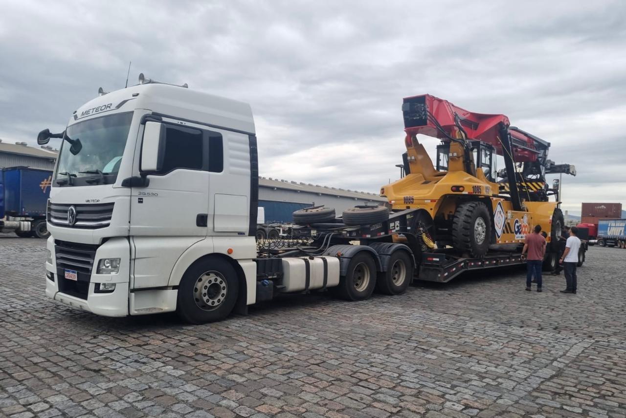 Caminhão Meteor com carreta prancha transportando Reach Stacker em porto