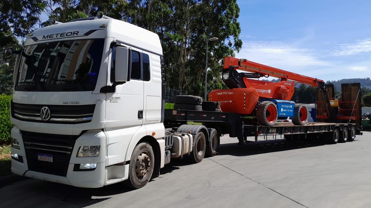 Caminhão Meteor com carreta prancha transportando plataforma elevatória articulada Tecnogera