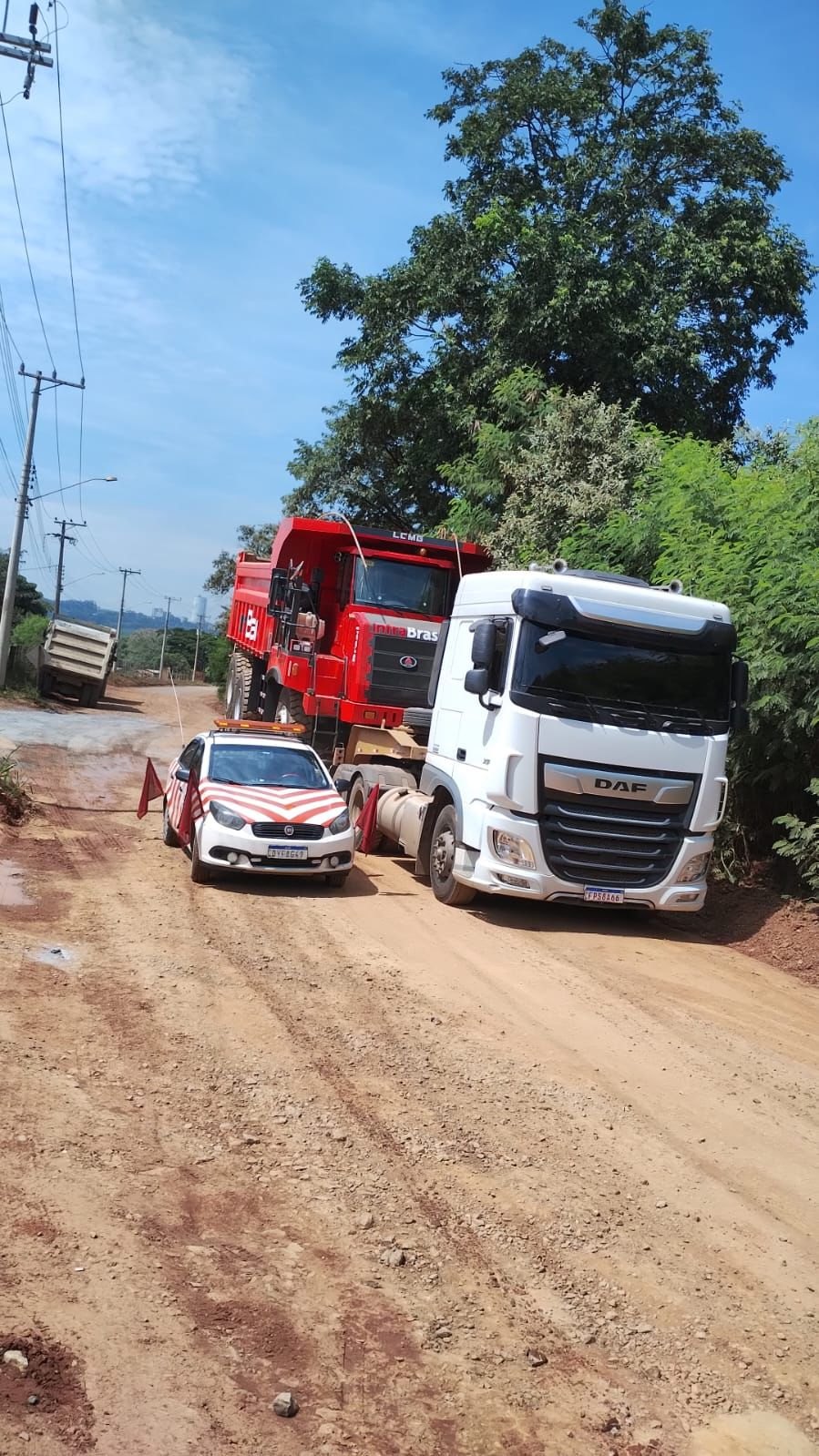 Caminhão DAF transportando caminhão fora de estrada com excesso lateral e de altura, acompanhado de batedor