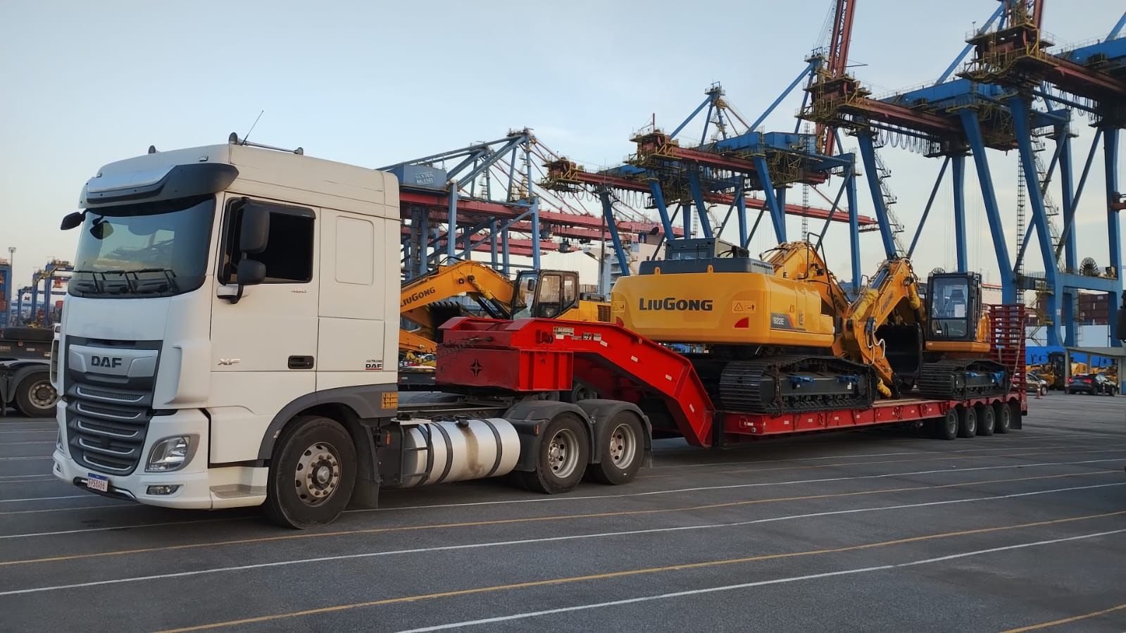 Caminhão DAF com prancha reta de 4 eixos transportando escavadeiras LiuGong em porto